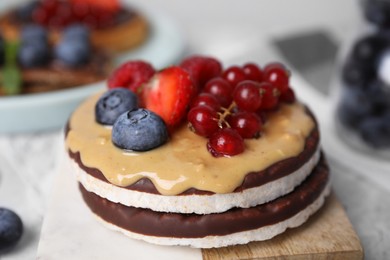 Crunchy rice cakes with peanut butter and sweet berries on table, closeup