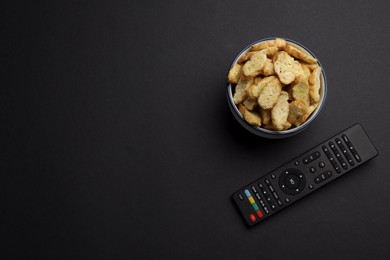 Modern tv remote control and rusks on black background, flat lay. Space for text