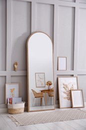 Photo of Light room interior with large mirror, beautiful pictures and pouf near wall
