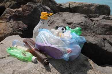 Garbage on stones near sea. Environmental Pollution concept