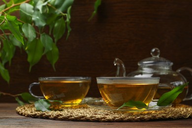 Photo of Fresh green tea in glass cups, leaves and teapot on wooden table