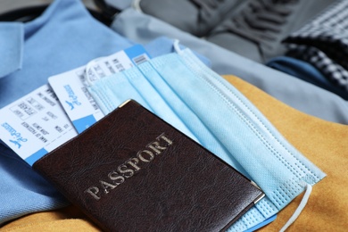 Passport with protective mask and tickets in suitcase, closeup