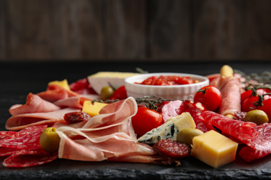 Photo of Tasty prosciutto with other delicacies served on table, closeup