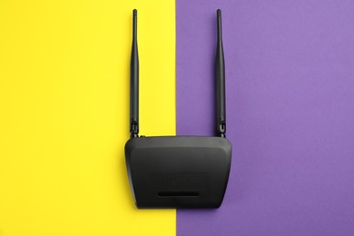 Modern Wi-Fi router on color background, top view