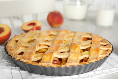 Delicious fresh peach pie on light kitchen table, closeup