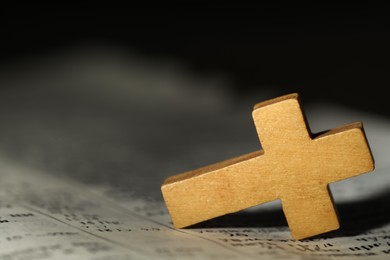 Wooden Christian cross on Bible, closeup. Space for text