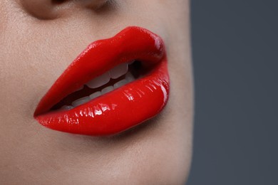 Photo of Young woman with beautiful red lips on grey background, closeup