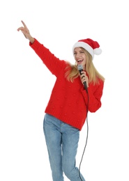 Happy woman in Santa Claus hat singing with microphone on white background. Christmas music