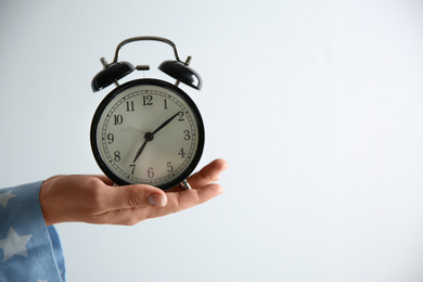 Woman holding alarm clock on white background, closeup. Morning time