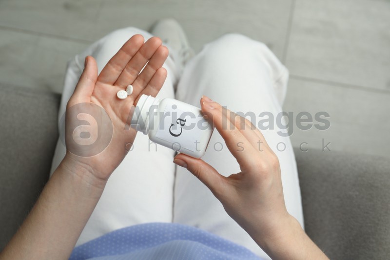 Calcium supplement. Woman taking pills indoors, top view