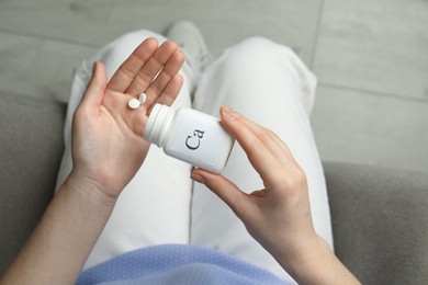 Calcium supplement. Woman taking pills indoors, top view