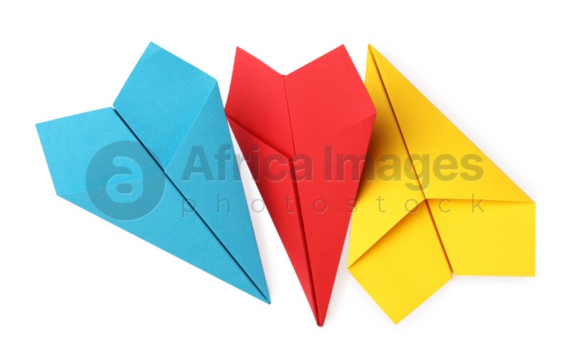Photo of Handmade yellow, light blue and red paper planes isolated on white, top view