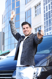 Photo of Man with key near car on city street. Buying new auto