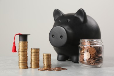 Photo of Scholarship concept. Piggy bank, graduation cap and coins on light grey table