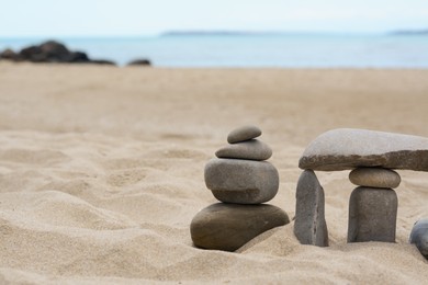 Stacks of stones on beautiful sandy beach near sea, space for text