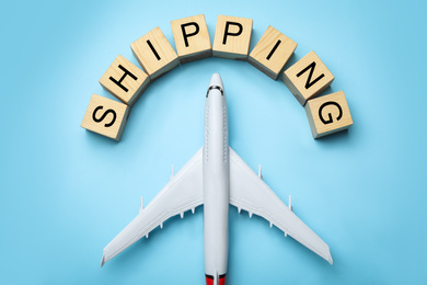 Toy plane with word SHIPPING on blue background, flat lay. Logistics and wholesale concept