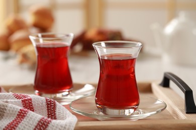 Photo of Glasses of traditional Turkish tea on wooden tray indoors