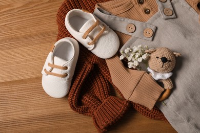 Children's shoes, clothes and toy on wooden table, closeup