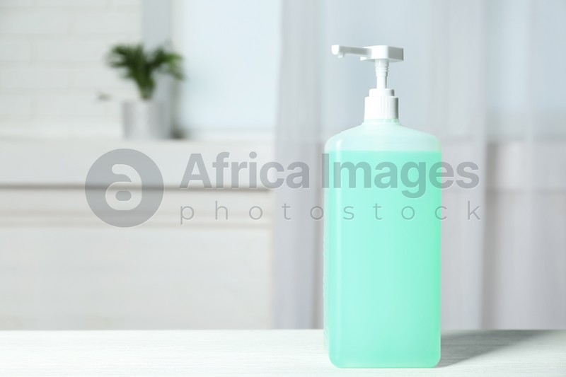Dispenser bottle with antiseptic gel on table indoors. Space for text