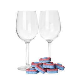 Wineglasses and many dishwasher detergent tablets on white background