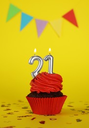 Delicious cupcake with number shaped candles on yellow background. Coming of age party - 21th birthday