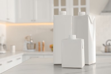 Photo of Carton boxes of milk on table in kitchen, space for text