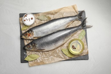 Slate plate with salted herrings, oil and spices on grey table, top view