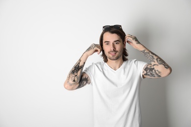 Young man with tattoos on arms against white background