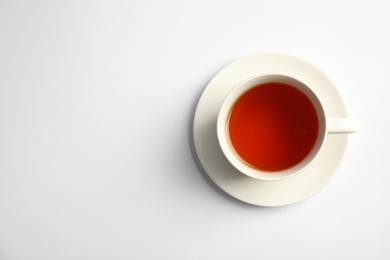 Cup of delicious tea with saucer on white background, top view