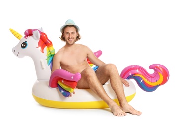 Attractive young man in swimwear with unicorn inflatable ring on white background