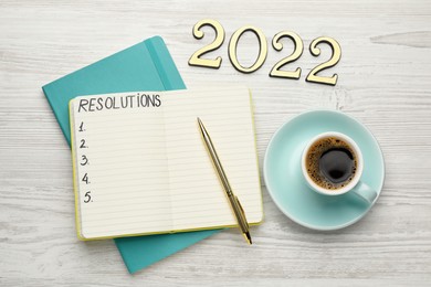 Making resolutions for 2022 new year. Flat lay composition with notebook on white wooden table