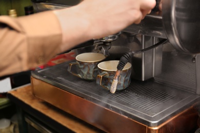 Barista preparing espresso using coffee machine, closeup