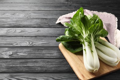 Fresh green bok choy cabbages on black wooden table. Space for text