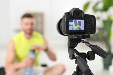 Photo of Trainer recording fitness lesson at home, focus on camera. Space for text