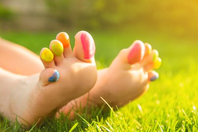 Teenage girl with painted toes on green grass outdoors, closeup