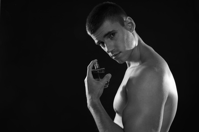 Photo of Handsome young man with bottle of perfume, black and white effect