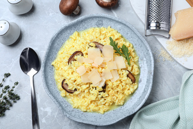 Delicious risotto with cheese and mushrooms on grey marble table, flat lay
