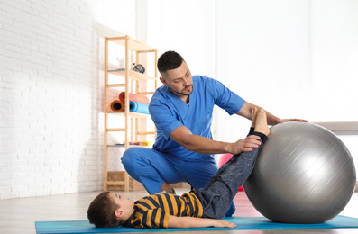 Orthopedist working with little boy in hospital gym