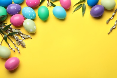 Bright painted eggs and pussy willows on yellow background, flat lay with space for text. Happy Easter