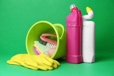 Bucket, cleaning supplies and tools on green background
