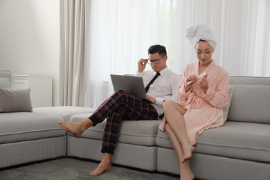 Man working on laptop while his wife relaxing in living room. Stay at home concept