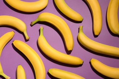 Ripe yellow bananas on purple background, flat lay