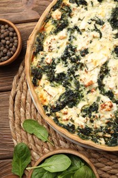 Photo of Delicious homemade quiche and spinach leaves on table, flat lay