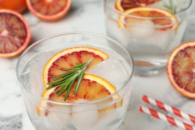 Delicious refreshing drink with sicilian orange and rosemary on white marble table, closeup