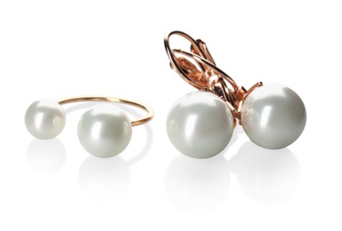 Elegant golden ring and earrings with pearls on white background
