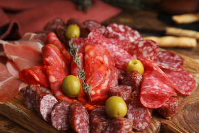 Photo of Tasty prosciutto with other delicacies served on wooden table, closeup
