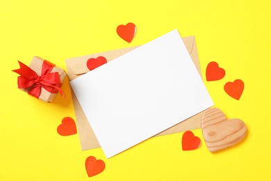 Flat lay composition with blank card on yellow background, space for text. Valentine's Day celebration