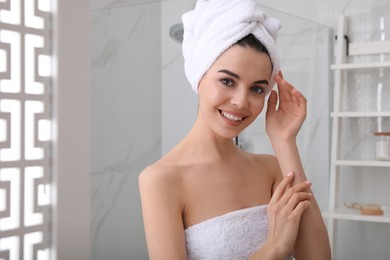 Happy young woman with towel on head in bathroom, space for text. Washing hair