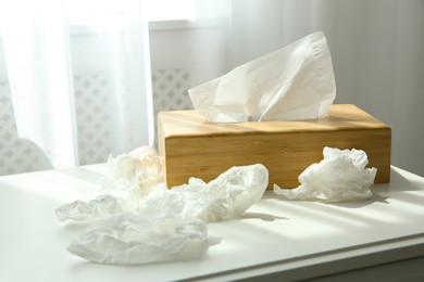 Used paper tissues and wooden holder on table near window