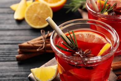 Aromatic punch drink and ingredients on black wooden table, closeup